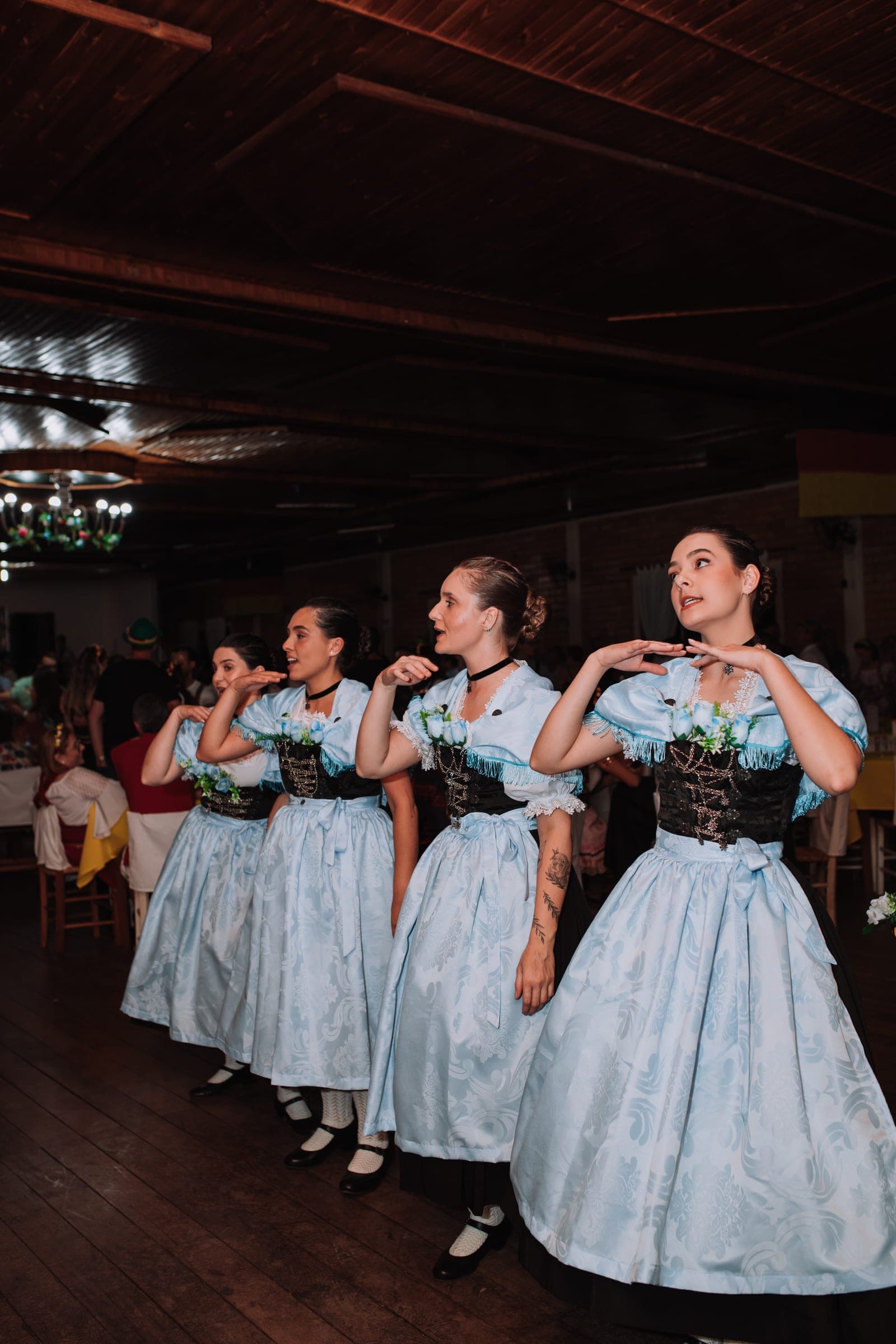 Fileira de dançarinas de vestido azul-claro e avental durante a coreografia