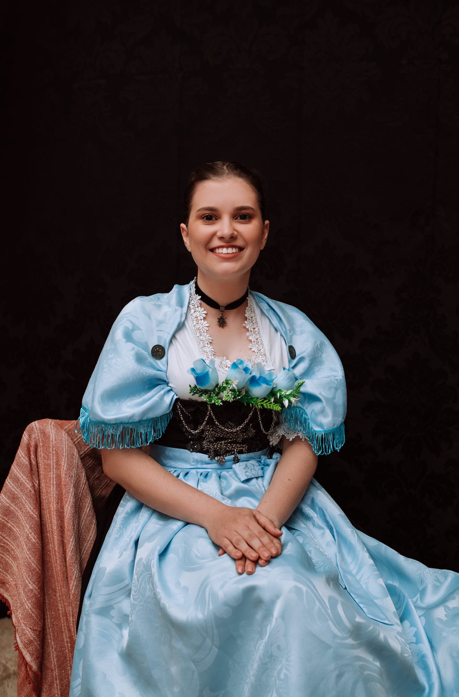 Dançarina do Tanzgruppe Rothenburg em traje típico azul-claro, sentada e sorrindo